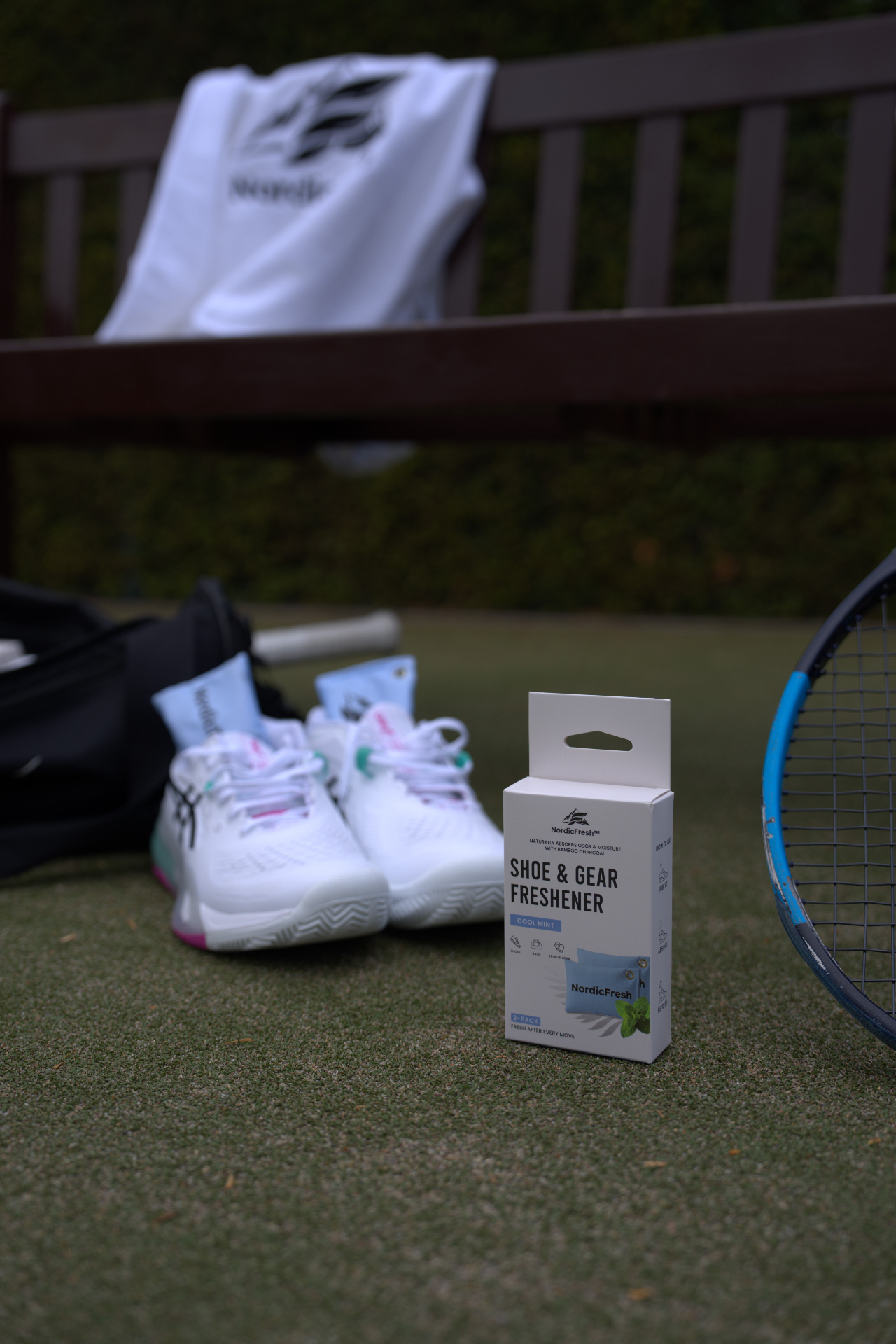 Athlete holding NordicFresh bamboo charcoal shoe & gear freshener packaging on the tennis court